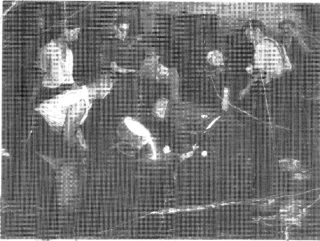 Black and white photograph of eight men working with molten metal